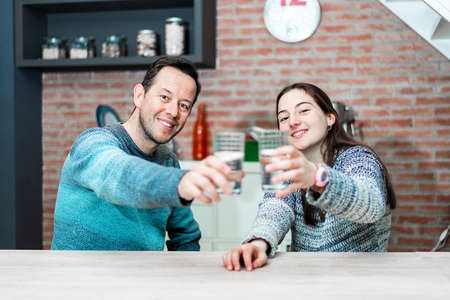 Two people holding a glass of water while looking at camera
