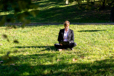 Businesswoman Sitting In Field Using Laptopの写真素材