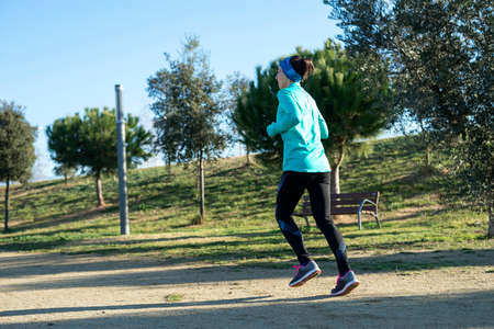 Young woman running outdoors in a city park in a sunny day