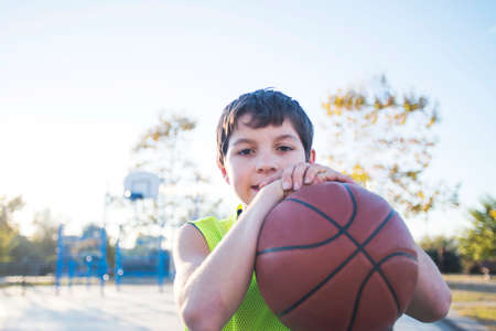 Young teen male with sleeveless standing on a street basket court while smiling at cameraの写真素材