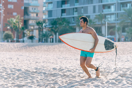 Surfer on the beach holding is surfboard and watching the wavesの写真素材