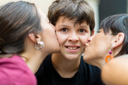 Upset little boy kissing by mom and sisterの写真素材