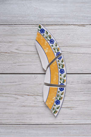 ceramic broken dish plate on wooden table.Flat lay
