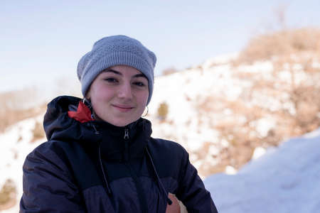 Young smiling woman in snowy mountains at sunset in winter.の写真素材