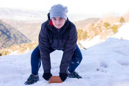 Young smiling woman in snowy mountains at sunset in winter.の写真素材