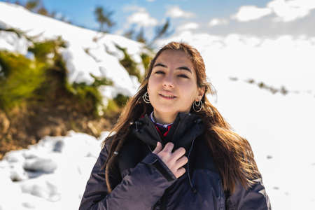 Young smiling woman in snowy mountains at sunset in winter.の写真素材