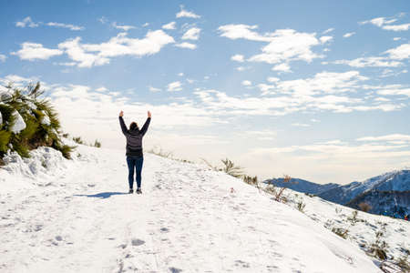 A Young traveler woman standing on snow mountain with arms raisedの写真素材