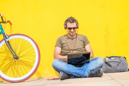 Young man working on laptop sitting on floor. Guy with computer reading news, surfing net or...