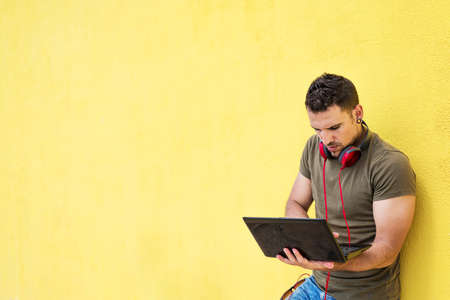 Portrait of an excited man holding laptop computer isolated on yellow background, Feeling happiness, Hispanic Male modelの写真素材