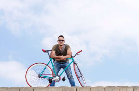 young hipster man riding fixed gear bike on city streetの写真素材