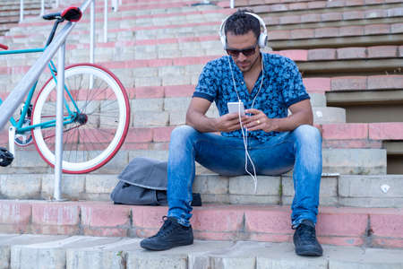 Young man relaxing on a bench while listening music (lifestyle)の写真素材