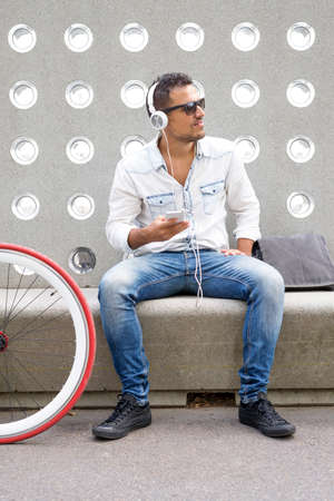 Young man relaxing on a bench while listening music (lifestyle)
