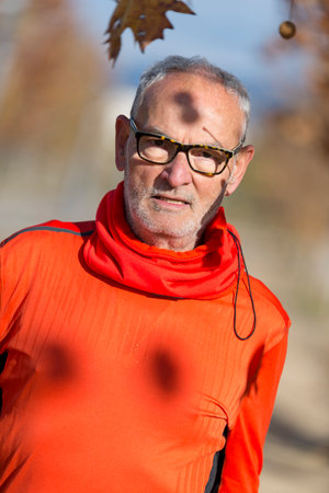 senior runner in orange sweatshirt in nature resting.の写真素材