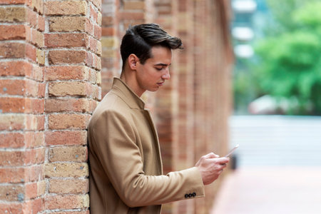 Young man wearing winter clothes in the street. Young guy with modern hairstyle with brown coat.の写真素材