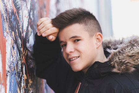 Teenager leaning against a wall in the street, looking at the camera.の写真素材