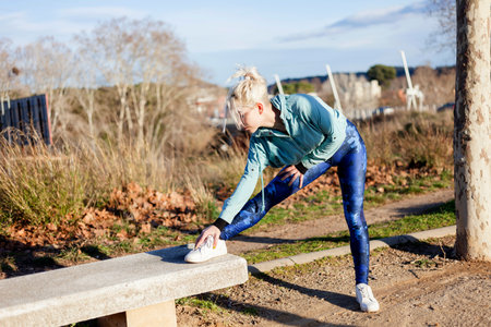 beautiful woman personal trainer stretching her legs outdoorsの写真素材