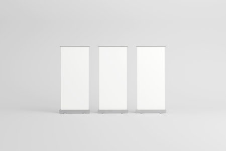 Three empty roll-up banners with white backgrounds, lined up side by side, ideal for customizable branding in exhibitions, trade shows, or promotional events.の写真素材