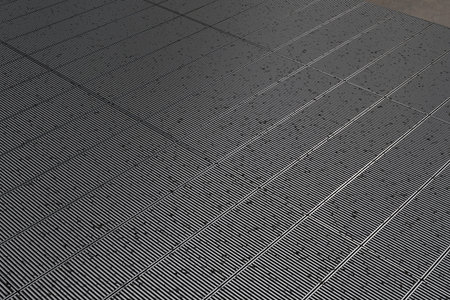 High-angle view of an industrial metal floor made of parallel ribbed panels forming a repeating grid...