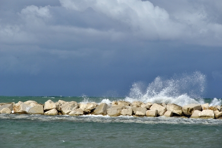 windy day at sea with big waves against rocksの写真素材
