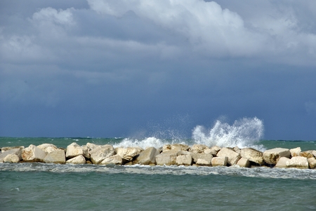 windy day at sea with big waves against rocksの写真素材
