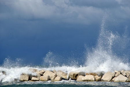 windy day at sea with big waves against rocksの写真素材