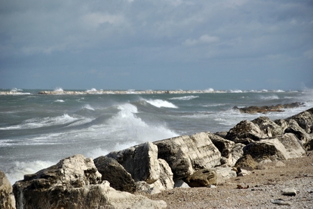 windy day at sea with big waves against rocksの写真素材