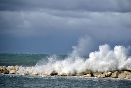 windy day at sea with big waves against rocksの写真素材