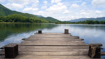 Panoramic view of Wooden bridge lake with Green mountain, bright blue sky and lake at the background with Empty wooden floor. can be used for display product Mock Up. Panoramic Nature Scene.の写真素材
