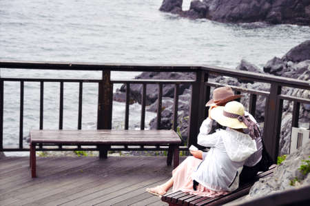 Candid shot of Couple on the bench. Couple sitting on the bench with lake view on background.の写真素材
