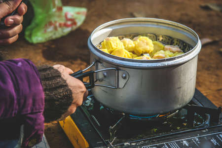 Rural way cooking. A woman's hand boiling dumplings in a pot. Woman Cooking food in the kitchen. Old woman's hand Cooking Dim sum in a hot pot. CULTURAL and EXOTIC FOODS Concept.の写真素材