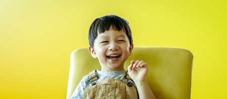 Portrait of happy smiling child boy isolated on yellow background. Portrait of happy joyful laughing beautiful little boy on yellow background.の写真素材
