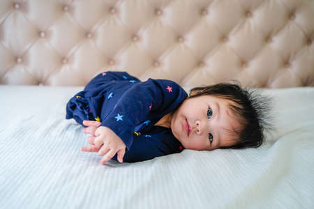 Cute little baby girl, playing at home in bed. Cute little caucasian baby lying on bed at home....