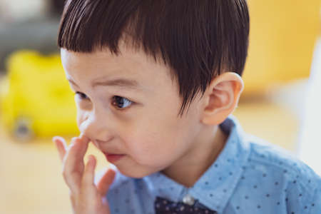 baby picking nose. little baby boy with finger in his nose. Cute little baby boy picking his nose, close up. children's behavior. Selective Focus.の写真素材