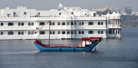 Traditional indian boat in front of the Lake Palace in Udaipur, India のeditorial素材