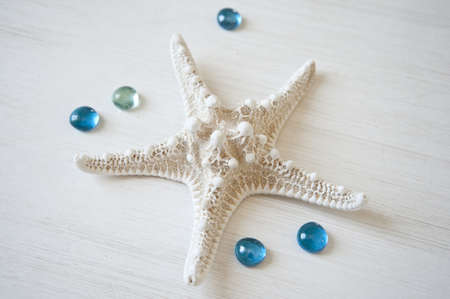 White starfish on a white wooden background with turquoise drops 