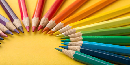 Vibrant colored pencils arranged in spectrum on sunny yellow background offer creative potential for art, design, and education projectsの写真素材