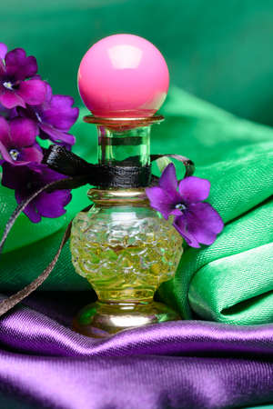 Small bottle of aroma oil decorated with violets and textileの写真素材