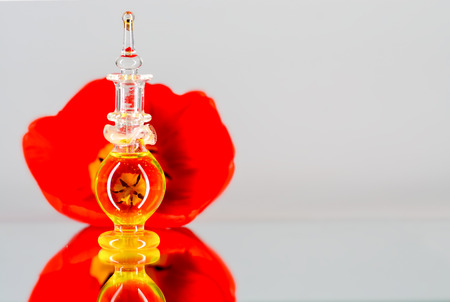 Small bottle of perfume on mirror surfaceの写真素材