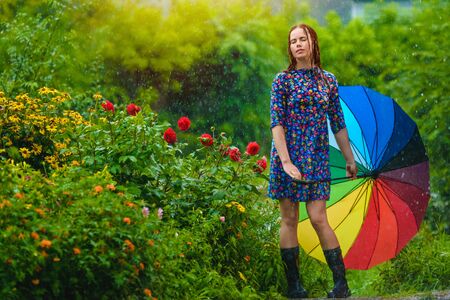 Young woman with bright umbrella wet under sunny rainの写真素材