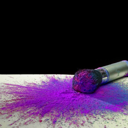 Makeup brush covered with bright holi dry powder paint