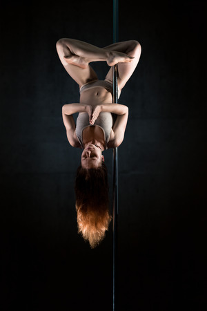 Young woman in meditation Lotus position upside down on poleの写真素材