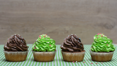 Four Small appetizing muffins on table with green textile surfaceの写真素材