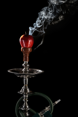 Smoking hookah with fruit head on dark background