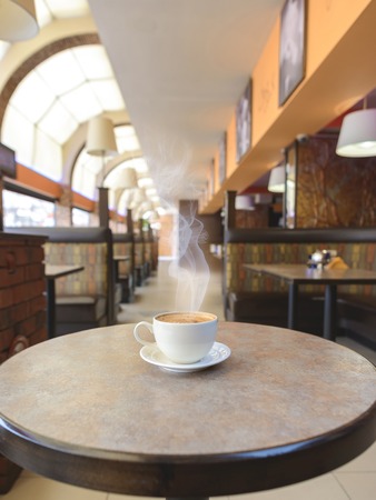White cup of capuccino at table in cafeの写真素材