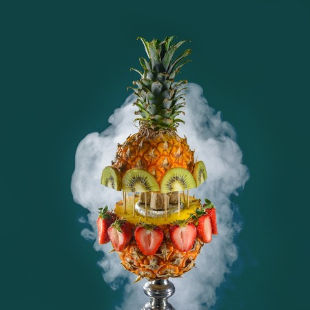 Smoking hookah with fruit head on dark background