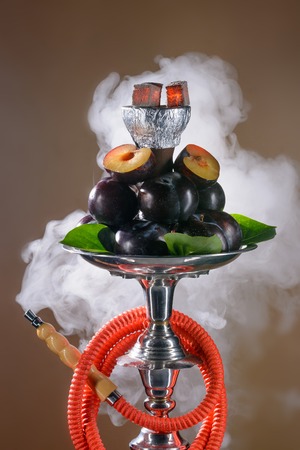 Smoking hookah with fruit tray on dark background