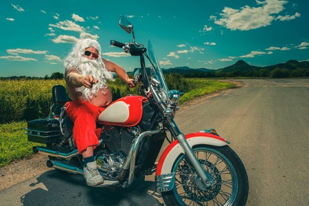 Sunburned Santa biker riding motorcycle on summer vacationsの写真素材