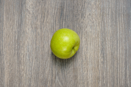 Single apple on a wooden table useful for designers