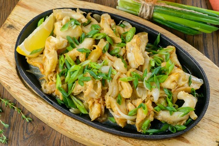 Fried clamps with greens on oval fry pan garnished with herbsの写真素材