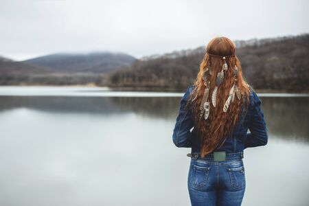 Long-haired girl on lake shore in autumn seasonの写真素材